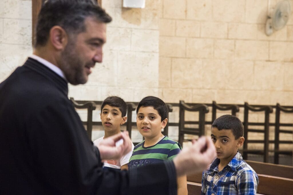 priest talks to children.