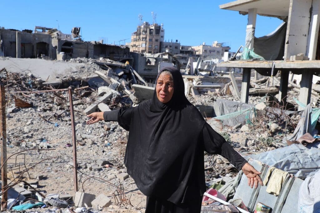 Woman walks on the rubble of her destroyed home in Gaza