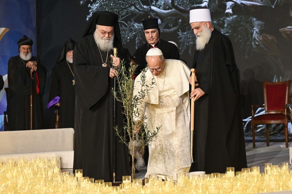 Pope Leo XIV waters an olive tree after he and other religious leaders planted it during an ecumenical and interreligious meeting.