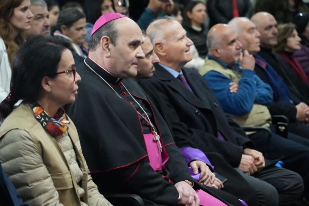 Apostolic Nuncio Paolo Borgia sitting among other people in a conference room.