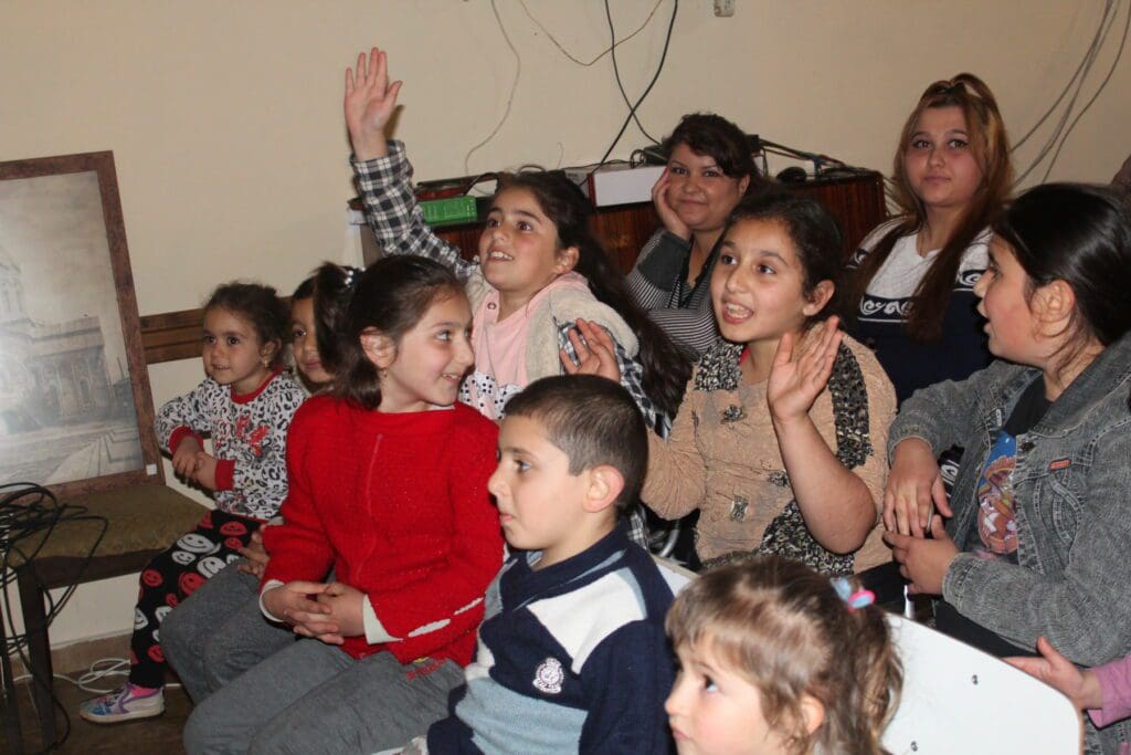 children raise their hands and call out during a lively exchange.