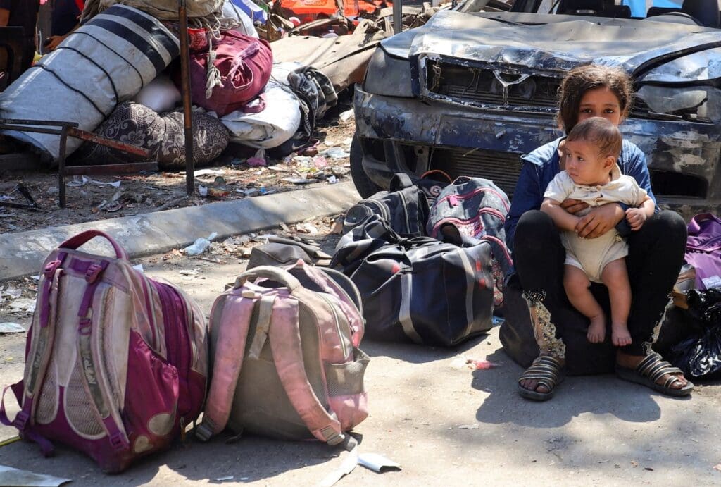 Sentada en una calle, una niña carga a su hermanito.