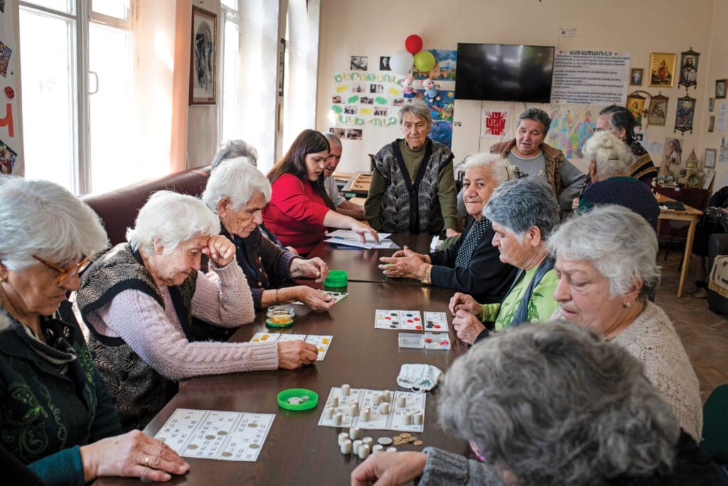 Un grupo de mujeres mayores sentadas en una mesa y jugando juegos de mesa.