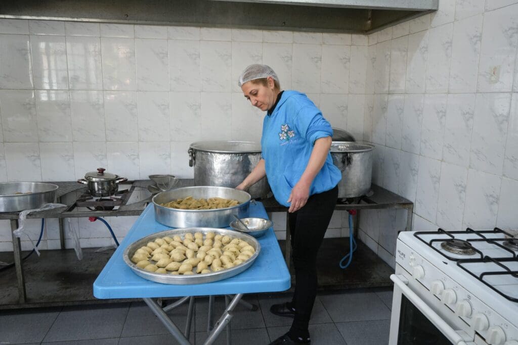 Una mujer con una camiseta azul trabaja en una cocina.