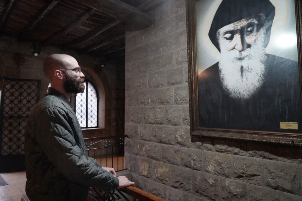 Un hombre mira un cuadro con una imagen de San Chárbel.