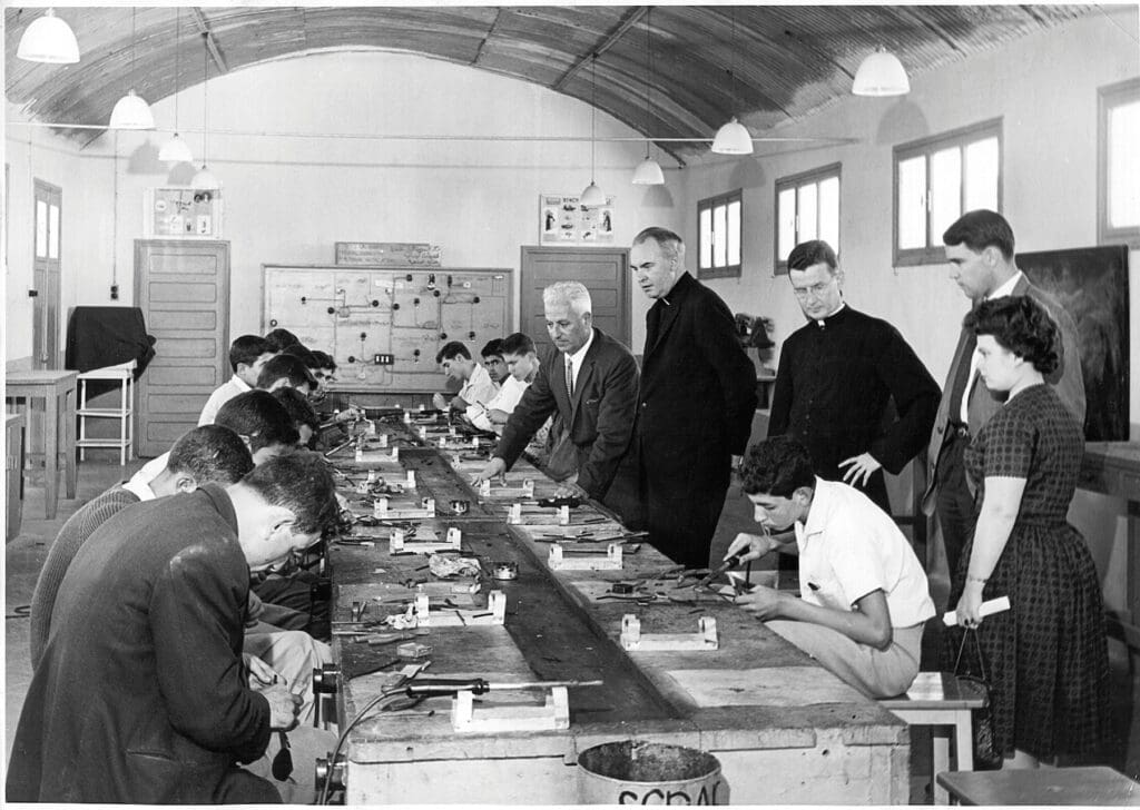 Mons. Joseph T. Ryan y Mons. Stephen J. Kelleher conversan con estudiantes en un aula técnica.
