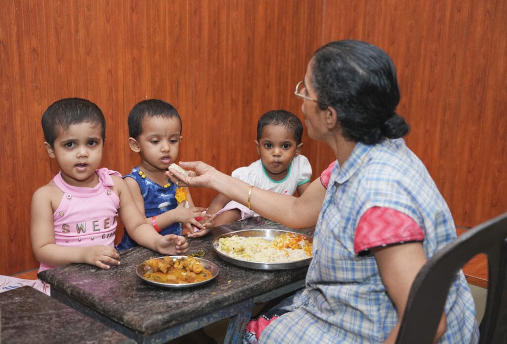 Una mujer da de comer a niños pequeños en un orfanato de la India.