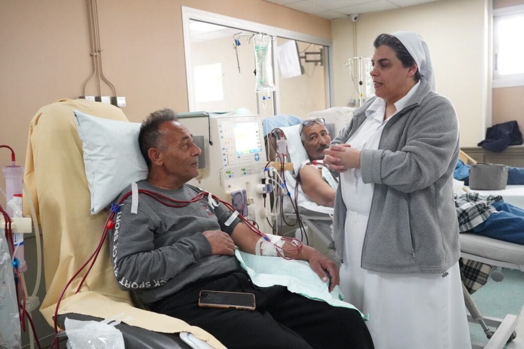 Una religiosa atiende a un hombre, un paciente, en una clínica.