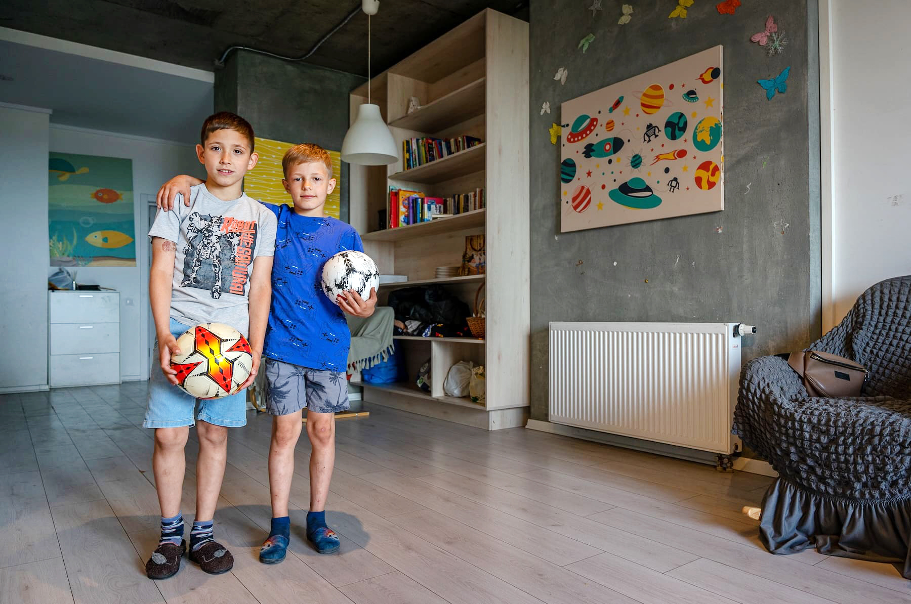 DIs niños ucranianos cargando una pelota de fútbol cada uno posan para la cámara.
