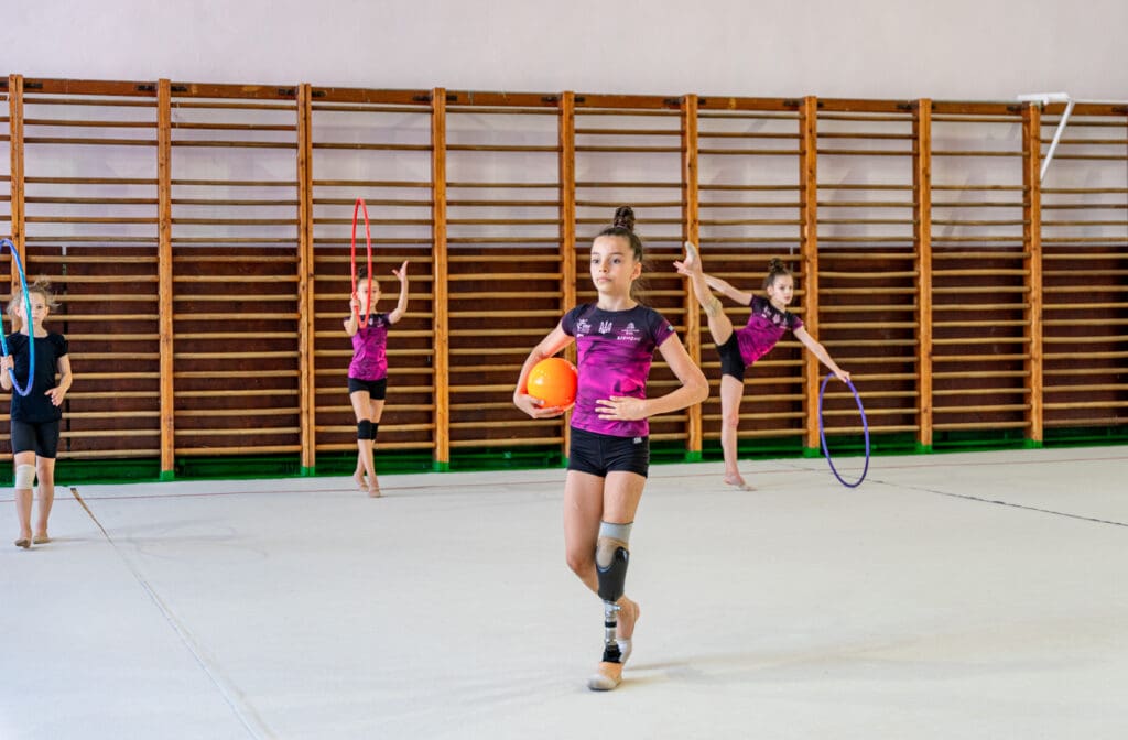 A gymnast girl with a prosthetic leg practices a floor routine.