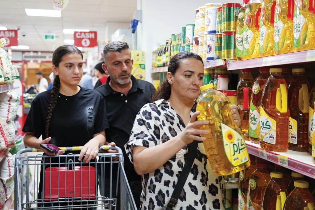 Un hombre, una mujer y una niña comprando alimentos en un supermercado.
