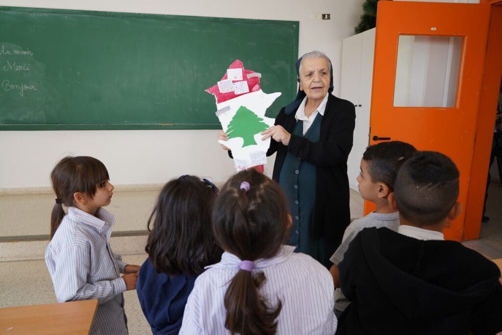Una religiosa muestra un mapa a unos niños en un aula.