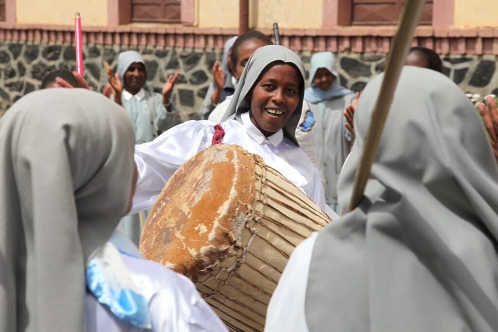 femme voilée jouant d'un grand tambour en plein air