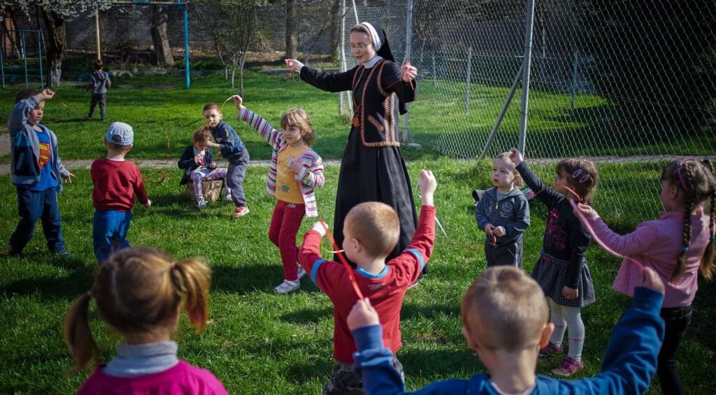 Una suora che gioca con dei bambini in un prato