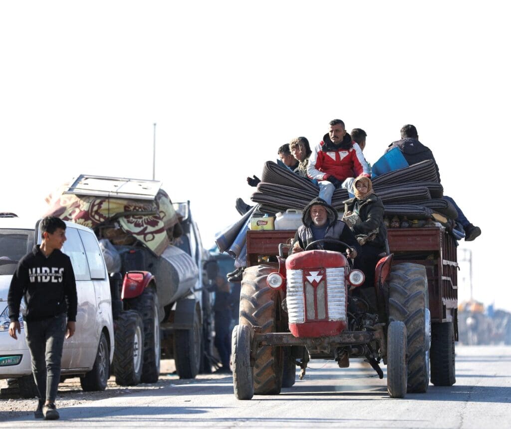 Un uomo guida un trattore che porta materassi e altre persone