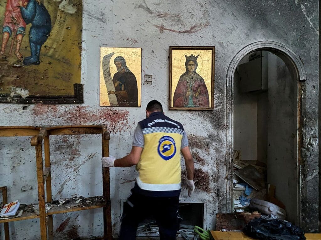 Un uomo sposta detriti all'interno di una chiesa distrutta