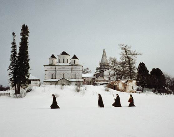 Quattro uomini vestiti di nero camminano in una distesa di neve.