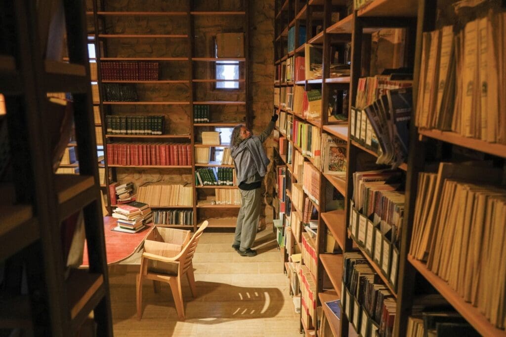 Una donna in biblioteca si allunga verso uno scaffale alto per prendere un libro.