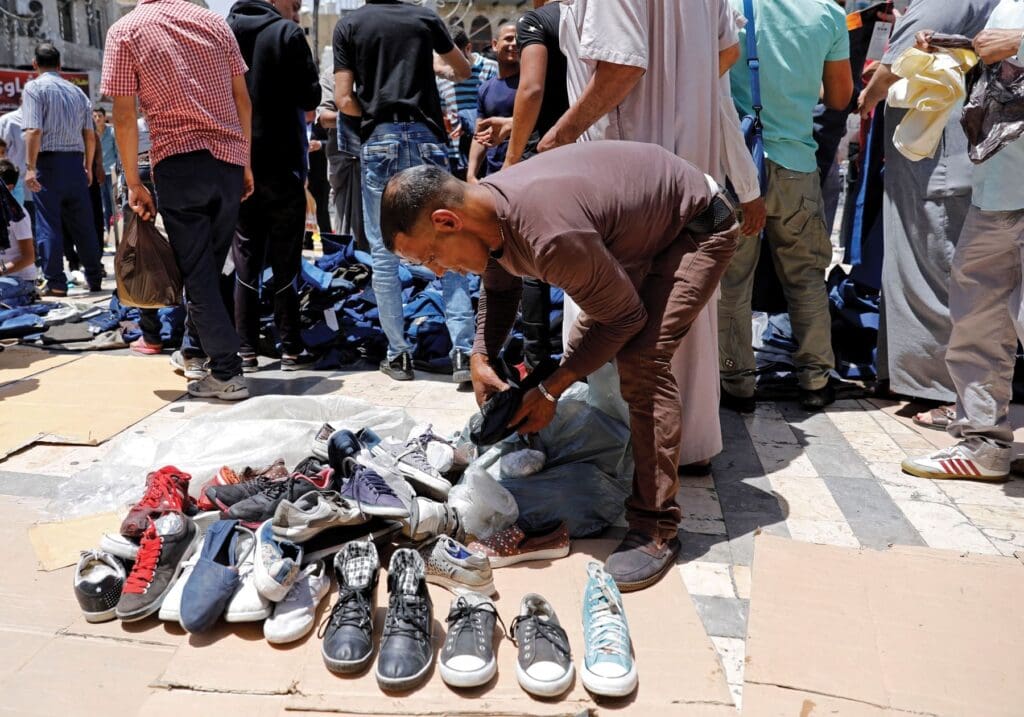Un uomo osserva scarpe usate in un mercato all’aperto nel centro di Amman.