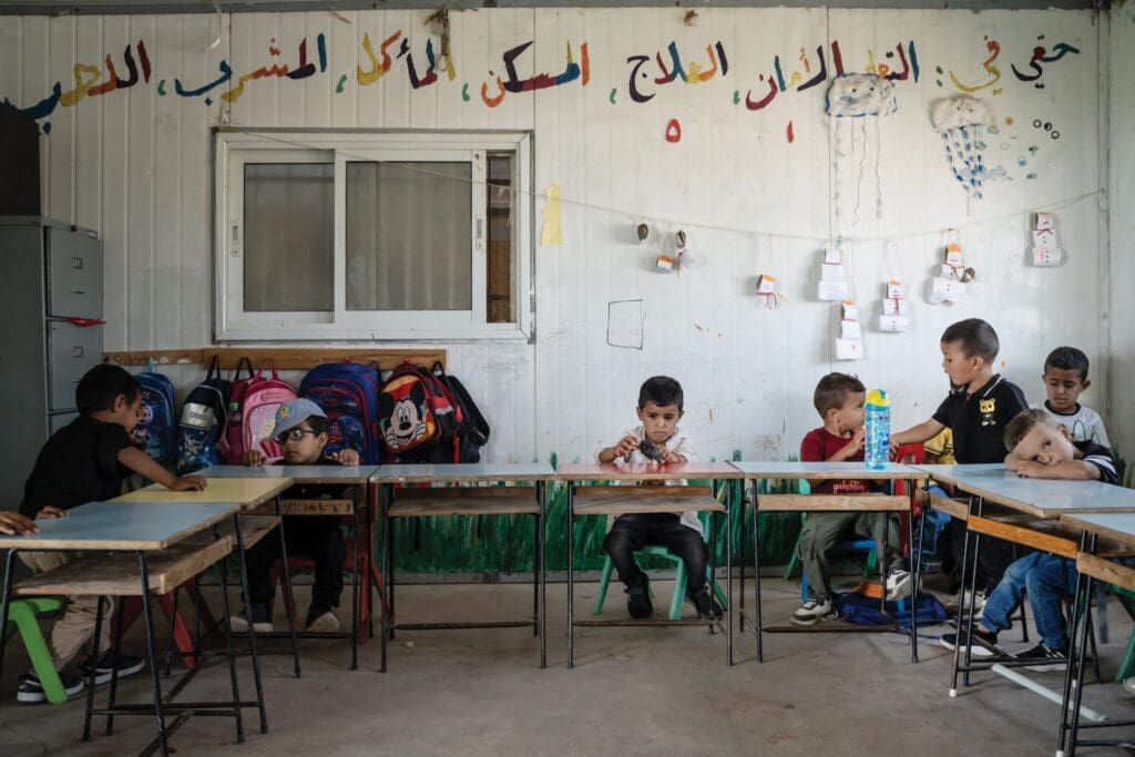 Bambini seduti ai banchi di un’aula di una scuola.