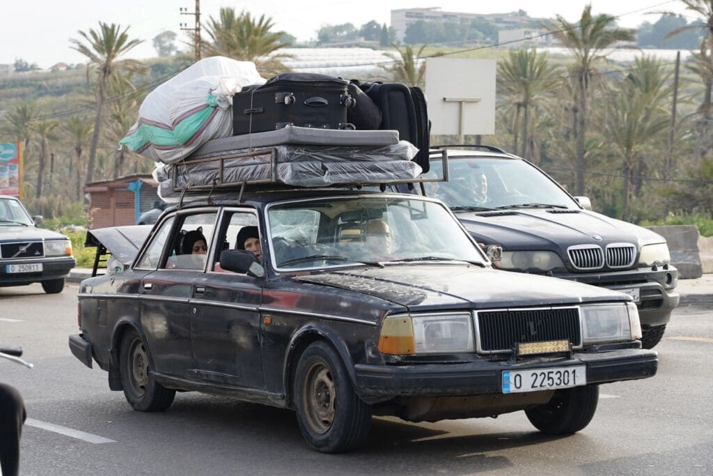 Un’automobile con materassi e bagagli sul tetto percorre una strada.