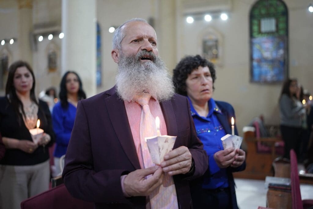 Un uomo e una donna con delle candele accese in mano in una chiesa.