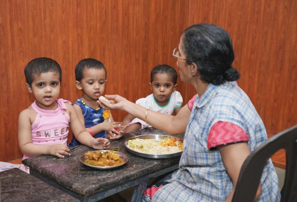 Una donna dà da mangiare a un gruppo di bambini piccoli.