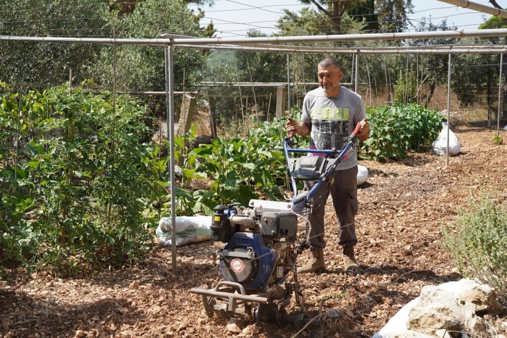 Un uomo con in mano un attrezzo mentre lavora un campo agricolo.