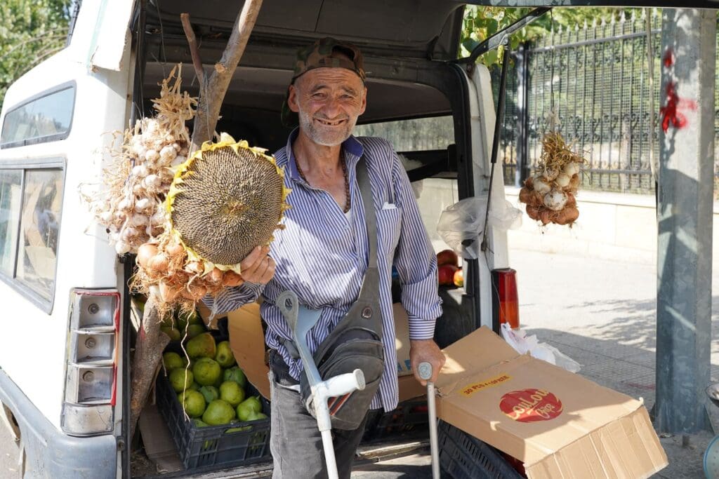 Un uomo con le stampelle tiene in mano un girasole.