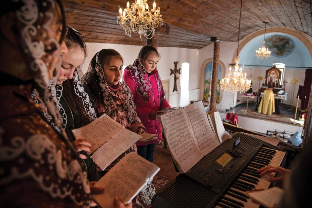 Church choir gathers around keyboard, overlooking the nave below.