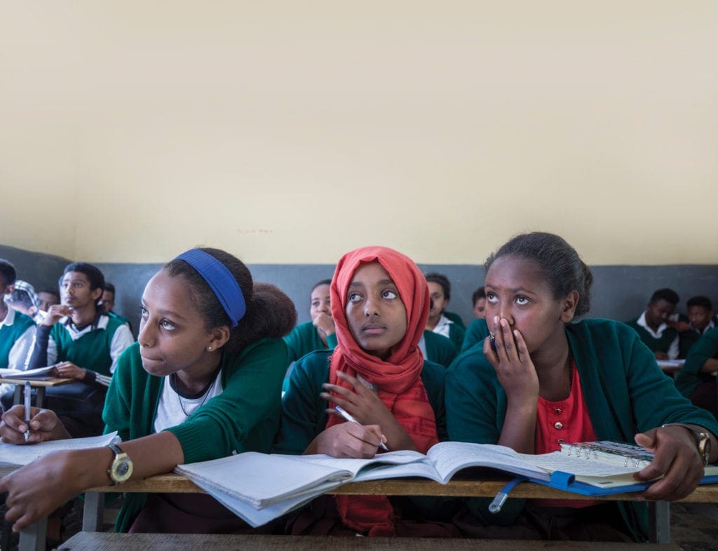 Students crowd together on benches to attend class in kidane mehret.