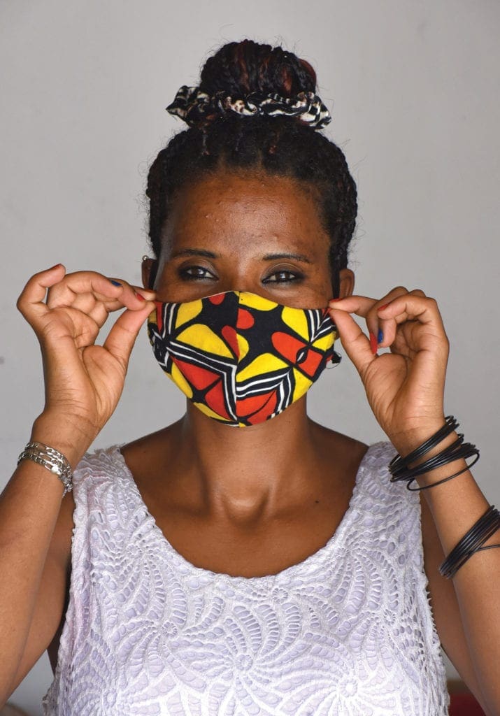 A woman models a mask she made, her smile visible in her eyes.