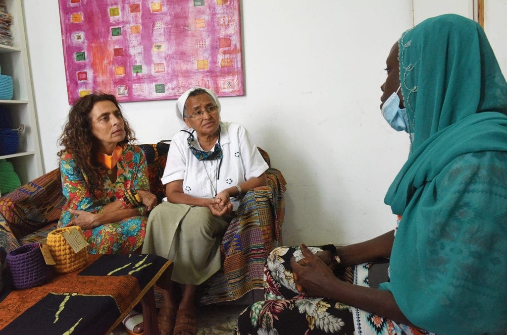 A nun and a doctor chat with a woman in their office, all seated.