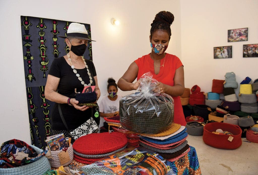 a woman wraps a handbag purchased by another woman at a store.