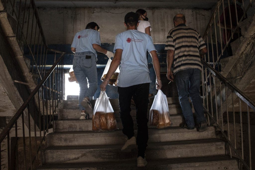 volunteers carry bags of bread up a flight of stairs.