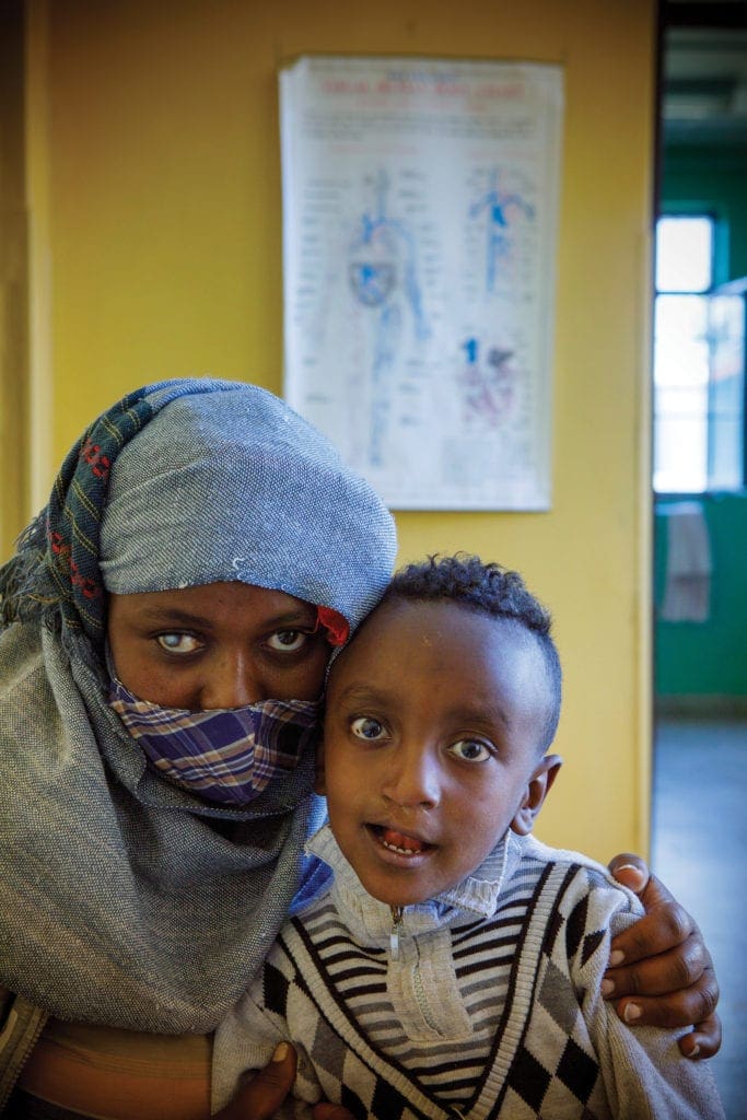 a woman and her son pose side by side.