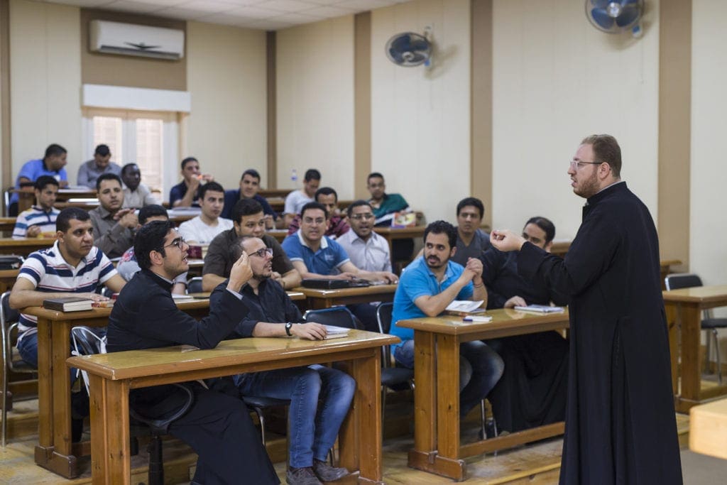 a priest lectures seminary students.