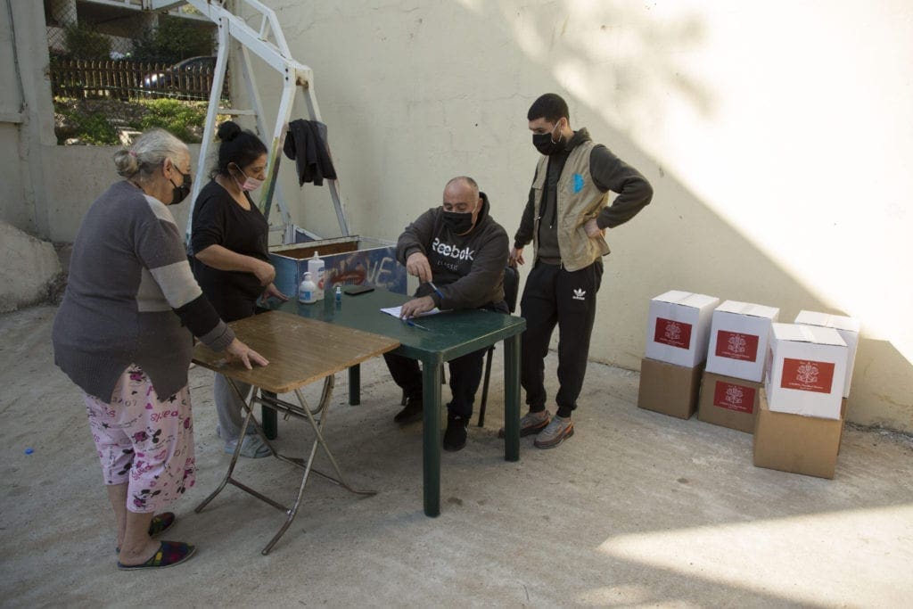 volunteers help to process a request for food at the Palestinian refugee camp in Dbayeh, Lebanon