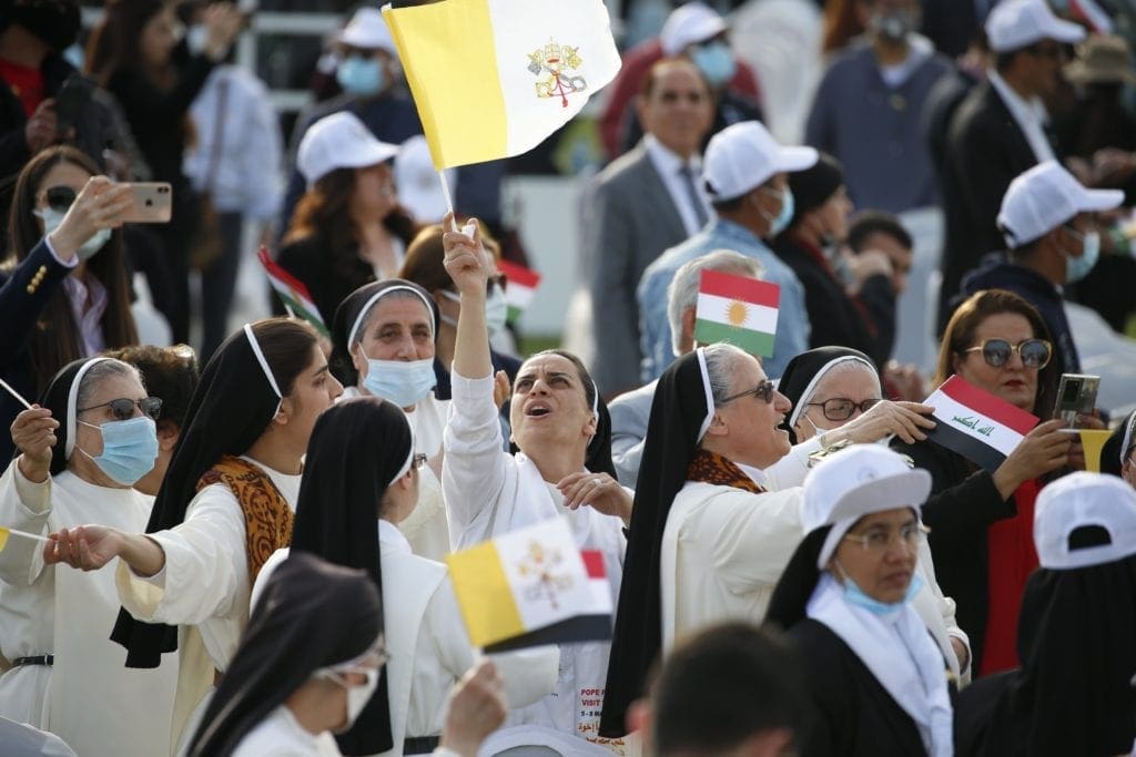 A nun waves a Vatican flag as she waits for Pope Francis to celebrate Mass at Franso Hariri Stadium in Erbil, Iraq.