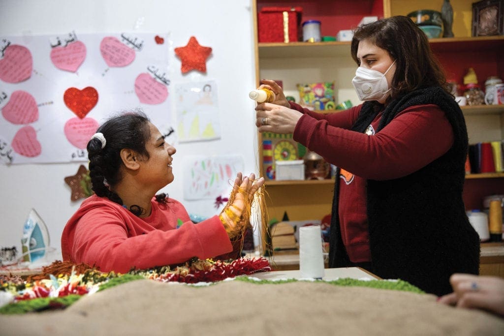 two women work on crafts.