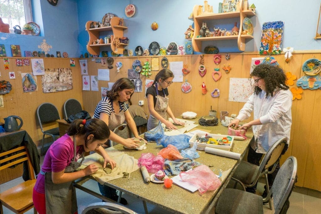 youth seated at a table work on crafts.