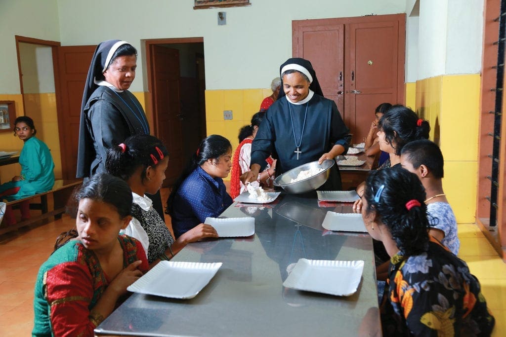 nuns serve lunch to a table of young women.