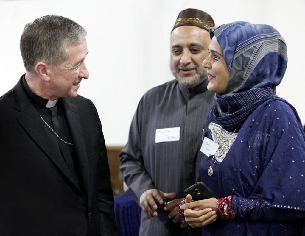 an archbishop greets Muslim colleagues at a Ramadan iftar.