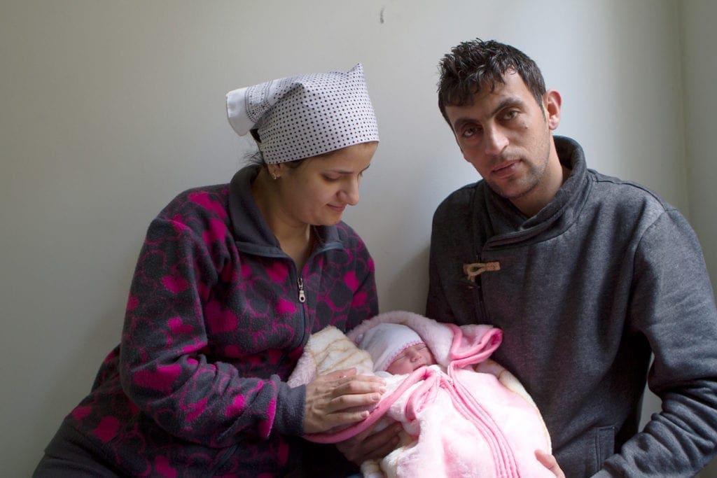 a young couple hold their swaddled newborn in Jordan.