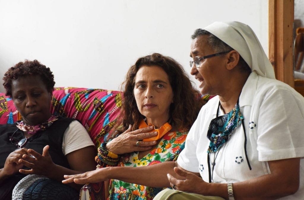 a nun sits with two migrant women in Israel.