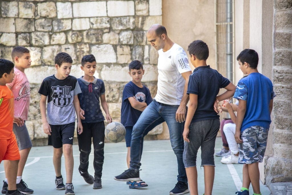 Adolescents kick around a soccer ball outside in Haifa, Israel.