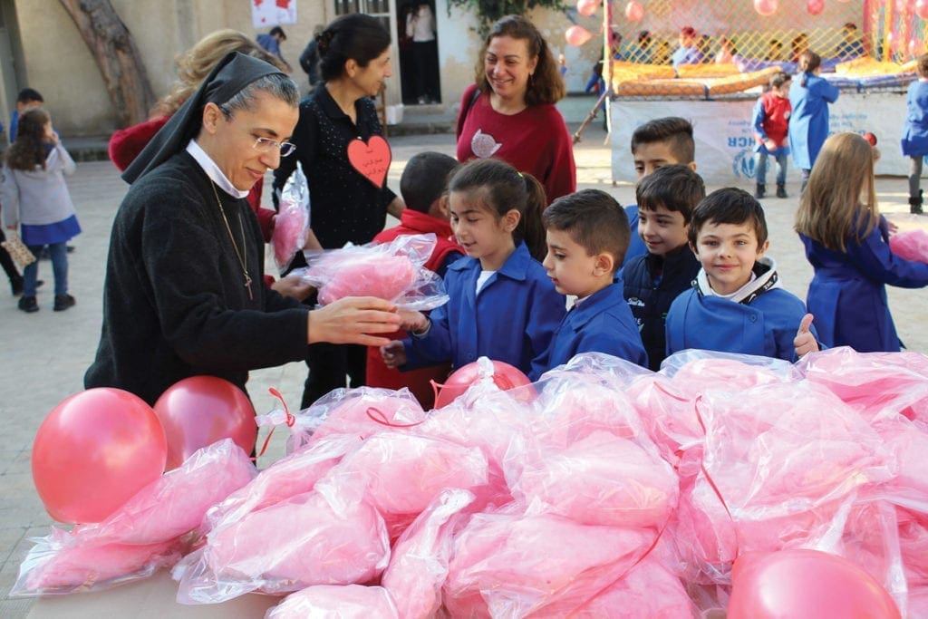 a nun hands out cotton candy to children.