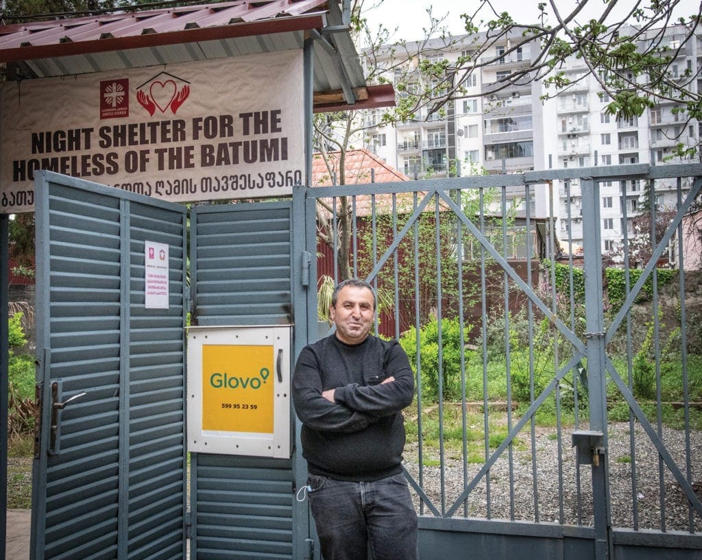 a man stands in front of the gate for the shelter in Batumi, Georgia.