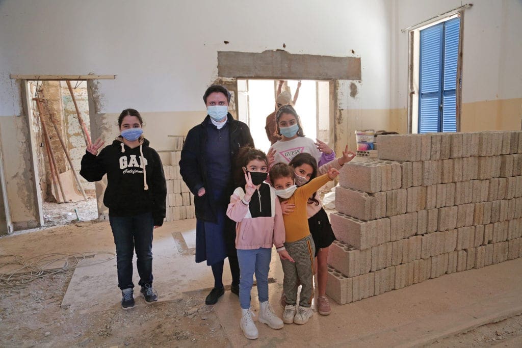 a nun and children look over a partially rebuild classroom.