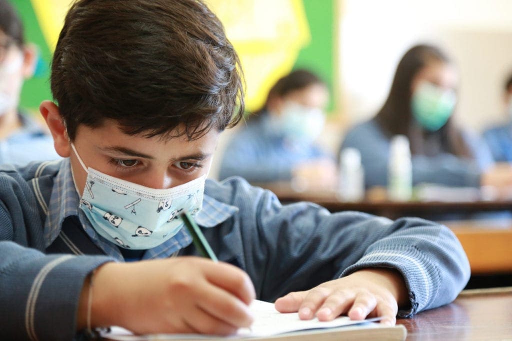 a masked student takes notes at Our Lady of Lebanon School.